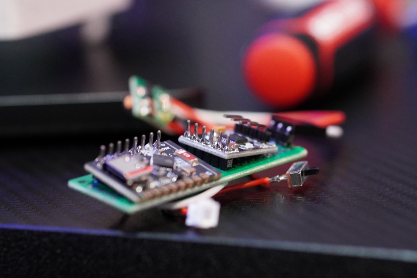 A small stack of microcontroller boards on the edge of the workbench